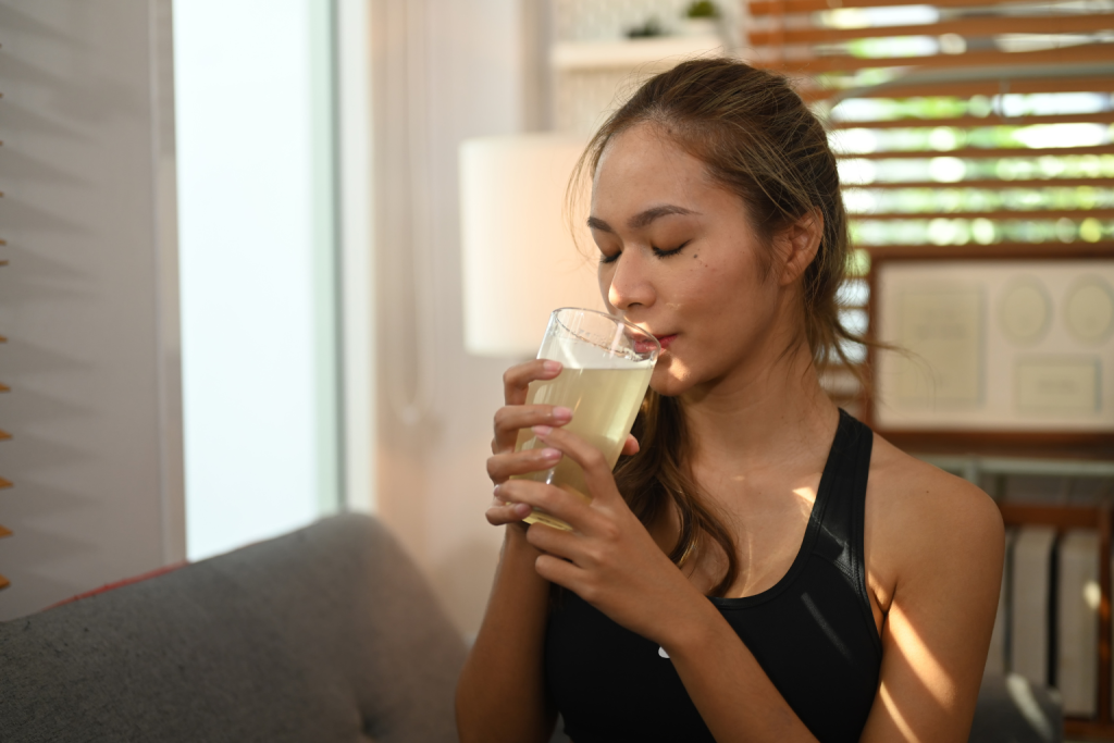 a woman sipping a glass of bone broth